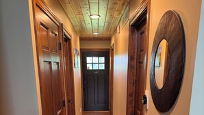 Un pasillo con piso de madera, un espejo grande en la pared y una puerta al final.