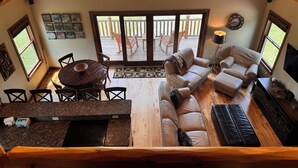 Un salón espacioso con techo de madera, una mesa de comedor con sillas, un sofá, un televisor y una chimenea.