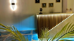 Zona de recepción con diseño moderno, que incluye un mostrador de recepción, un reloj de pared y un globo decorativo.