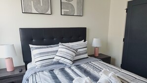 A neatly made bed with striped bedding and pillows, two bedside lamps, and a set of towels on the bed. - Luxury Urban Escape with Rooftop in downtown Atlanta (Atlanta)