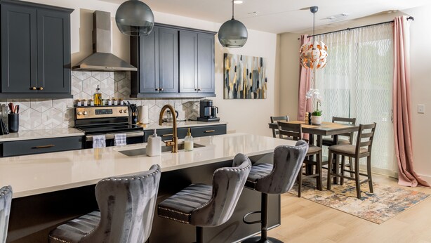 A modern kitchen with dark cabinets, a central island with bar stools, and pendant lighting. - Luxury Urban Escape with Rooftop in downtown Atlanta (Atlanta)