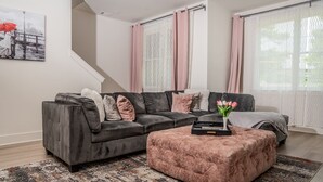 A modern living room with a grey sectional sofa, a pink ottoman, and a patterned rug. - Luxury Urban Escape with Rooftop in downtown Atlanta (Atlanta)