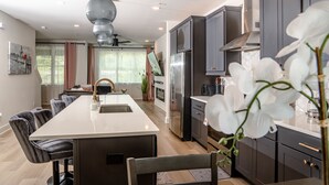 A modern kitchen with dark cabinets, a central island, and a dining area with chairs. - Luxury Urban Escape with Rooftop in downtown Atlanta (Atlanta)