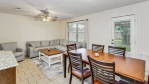 Un vaste salon comprenant un coin repas, un ventilateur de plafond et une vue sur le jardin à travers une porte-fenêtre coulissante.