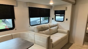 Un intérieur de camping-car compact comprenant un coin repas, des sièges et des fenêtres.