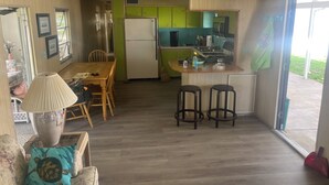 Un espace de vie compact comprenant un coin repas, une cuisine et une grande fenêtre.