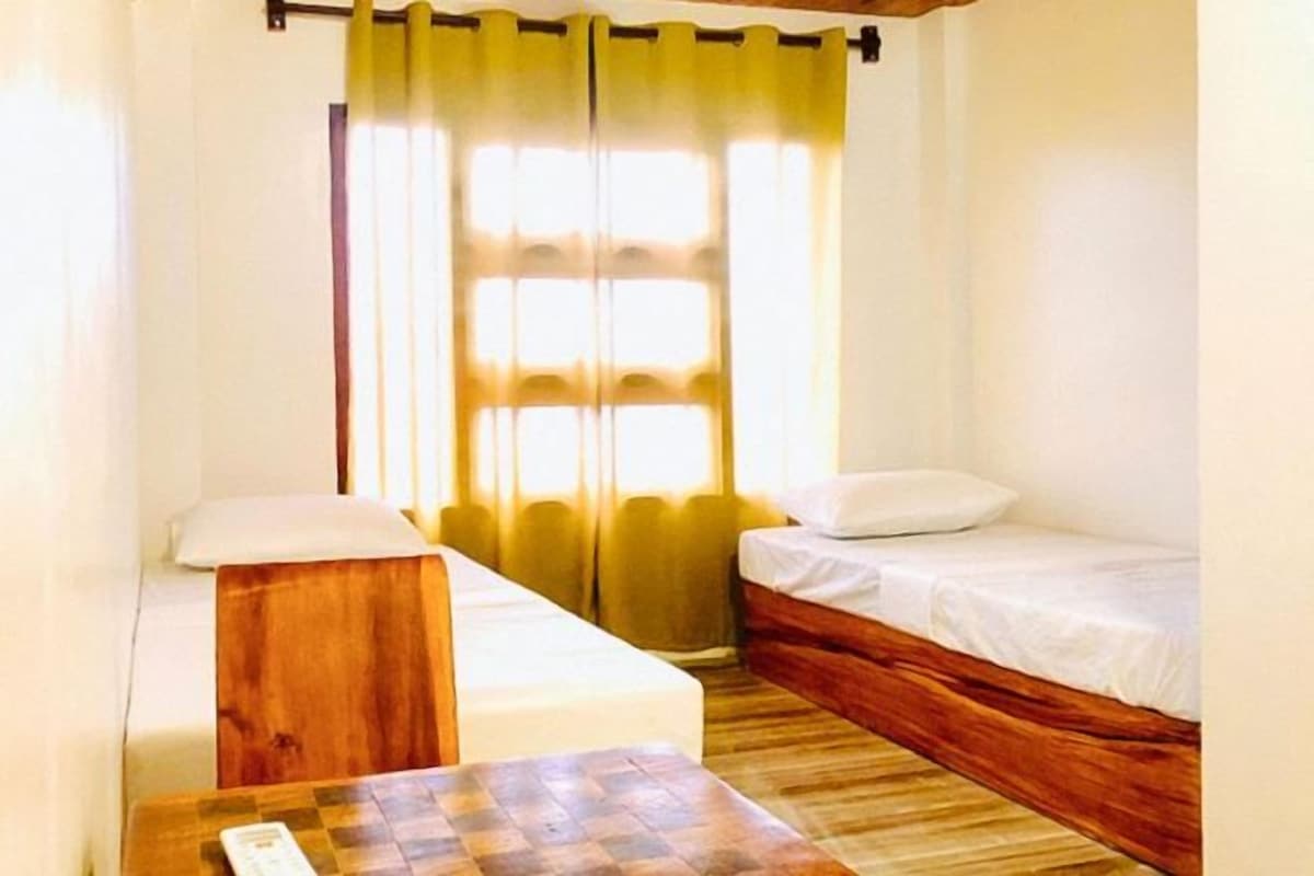 Una habitació petita i acollidora amb un llit individual, una petita taula de nit de fusta i una taula.