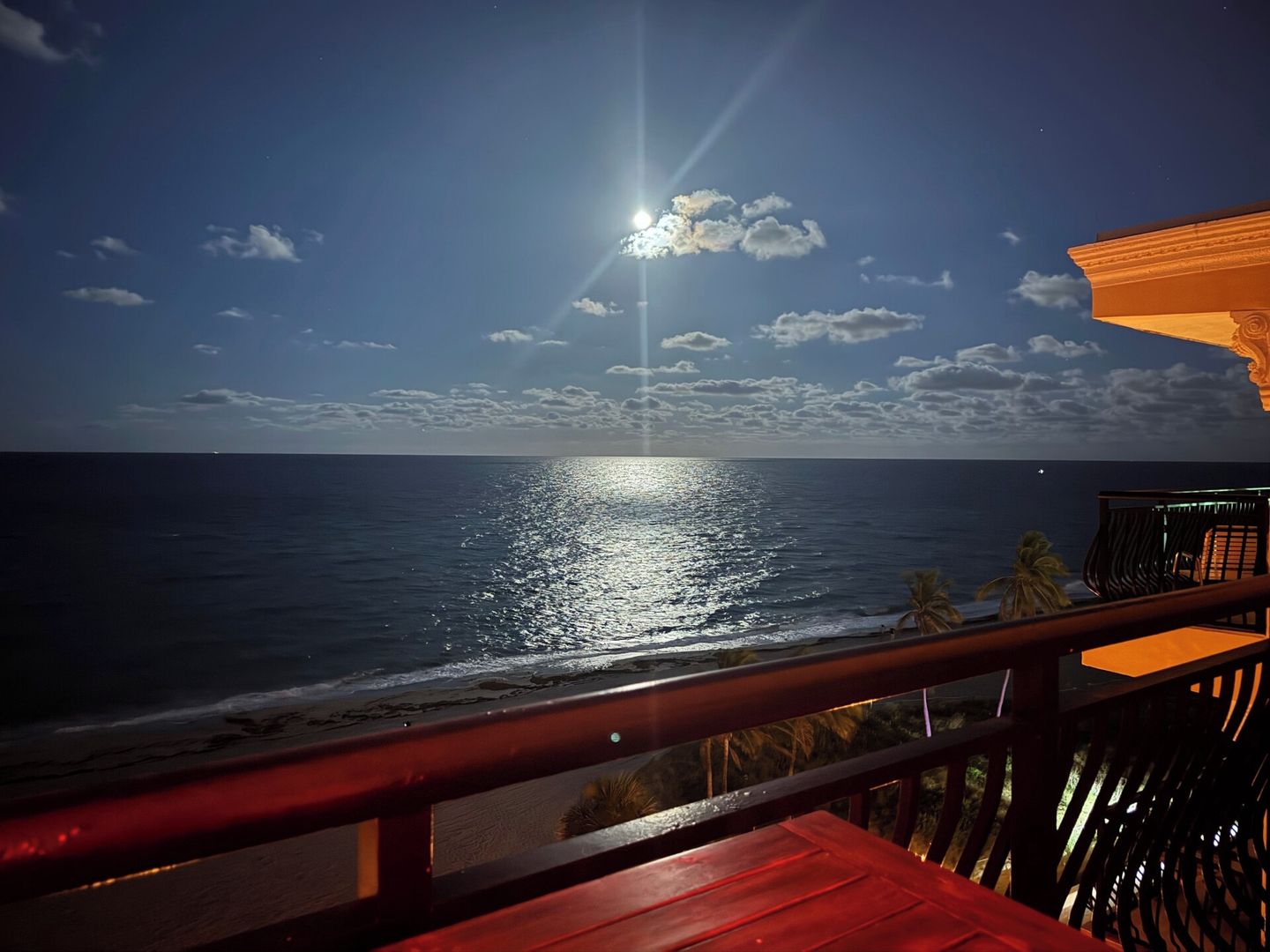 A beach view with a wooden deck and a railing.