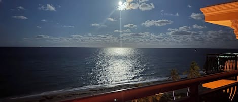 A beach view with a wooden deck and a railing.