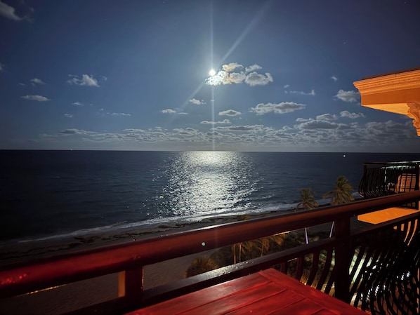 A beach view with a wooden deck and a railing.