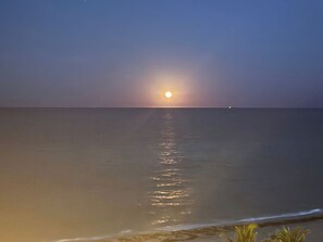 A calm sea at sunset with a visible horizon line.