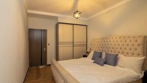 Un dormitorio con una cama grande, un armario y una lámpara colgante.