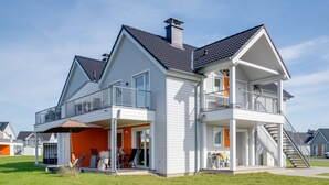 Ein zweistöckiges Haus mit Balkon, überdachter Veranda und sichtbarer Treppe.