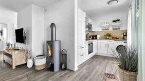Eine moderne Küche mit weißen Schränken, einem eingebauten Herd und einem Essbereich mit Holztisch und Stühlen.