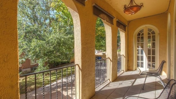A covered outdoor area with a patio, metal chairs, and a view of trees. - Italian Villa next to Gathering Place with pool (Tulsa)