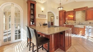 A spacious kitchen with a large island, wooden cabinets, and a built-in oven. - Italian Villa next to Gathering Place with pool (Tulsa)