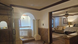 A spacious living area with a fireplace, a large window, and a ceiling fan. - Italian Villa next to Gathering Place with pool (Tulsa)