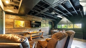 A modern interior with exposed ceilings, a stone wall, a fireplace, leather seating, and a dining area.