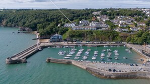 A coastal marina with numerous boats docked, surrounded by residential buildings and lush greenery. - Captains View - Sea and Harbour Views Parking (Saundersfoot)