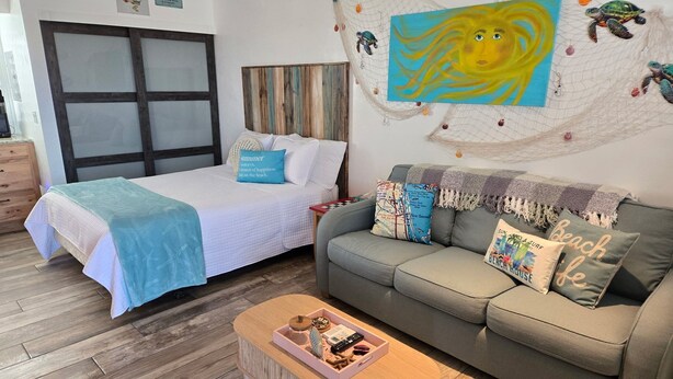 Una habitación con una cama, un sofá, una mesa de centro y una pared con un cuadro.