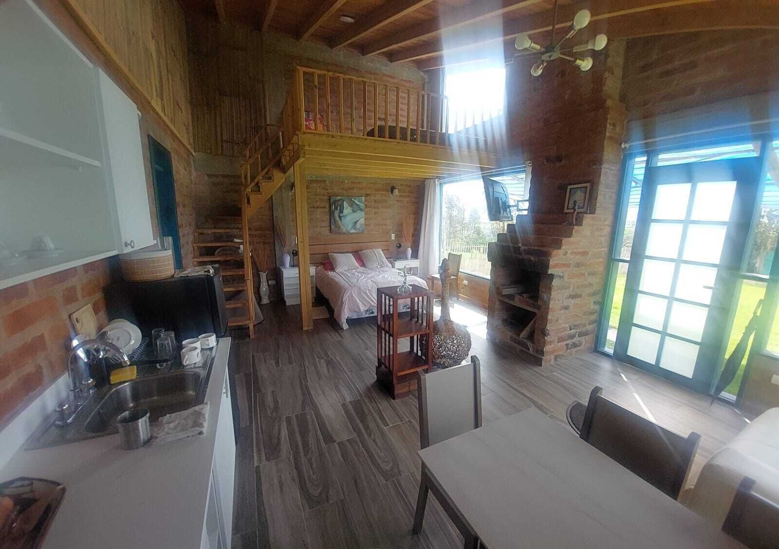 Een rustiek chalet interieur met een slaapkamer op de entresol, een eethoek en een keuken.
