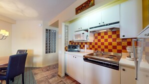A compact kitchen with white cabinets, a microwave, a toaster, and a coffee maker.