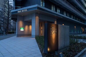 Het uiterlijk van het R&B Hotel, met een moderne gevel, een opvallend bord en een hekwerk.