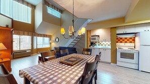 A cozy kitchen with a dining table, chairs, and a staircase leading to an upper level. - 1-511 : Condo - 1 bedroom - sleeps 4 (Beaupré)