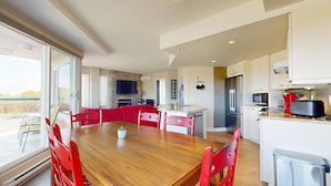 A modern kitchen with a dining area, large windows, and a stone accent wall.