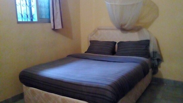 Una cama con dosel, una ventana con cortinas y una pared estampada.
