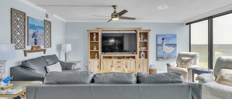 Ein modernes Wohnzimmer mit einem grauen Sofa, einer Holz-Unterhaltungsecke und einem großen Fernseher.