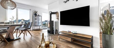 A modern living room with a large TV, wooden furniture, and a fireplace.