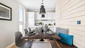 Un espace repas moderne avec une table en bois dressée pour six personnes, entourée de chaises. Un banc avec un coussin bleu est adossé au mur.