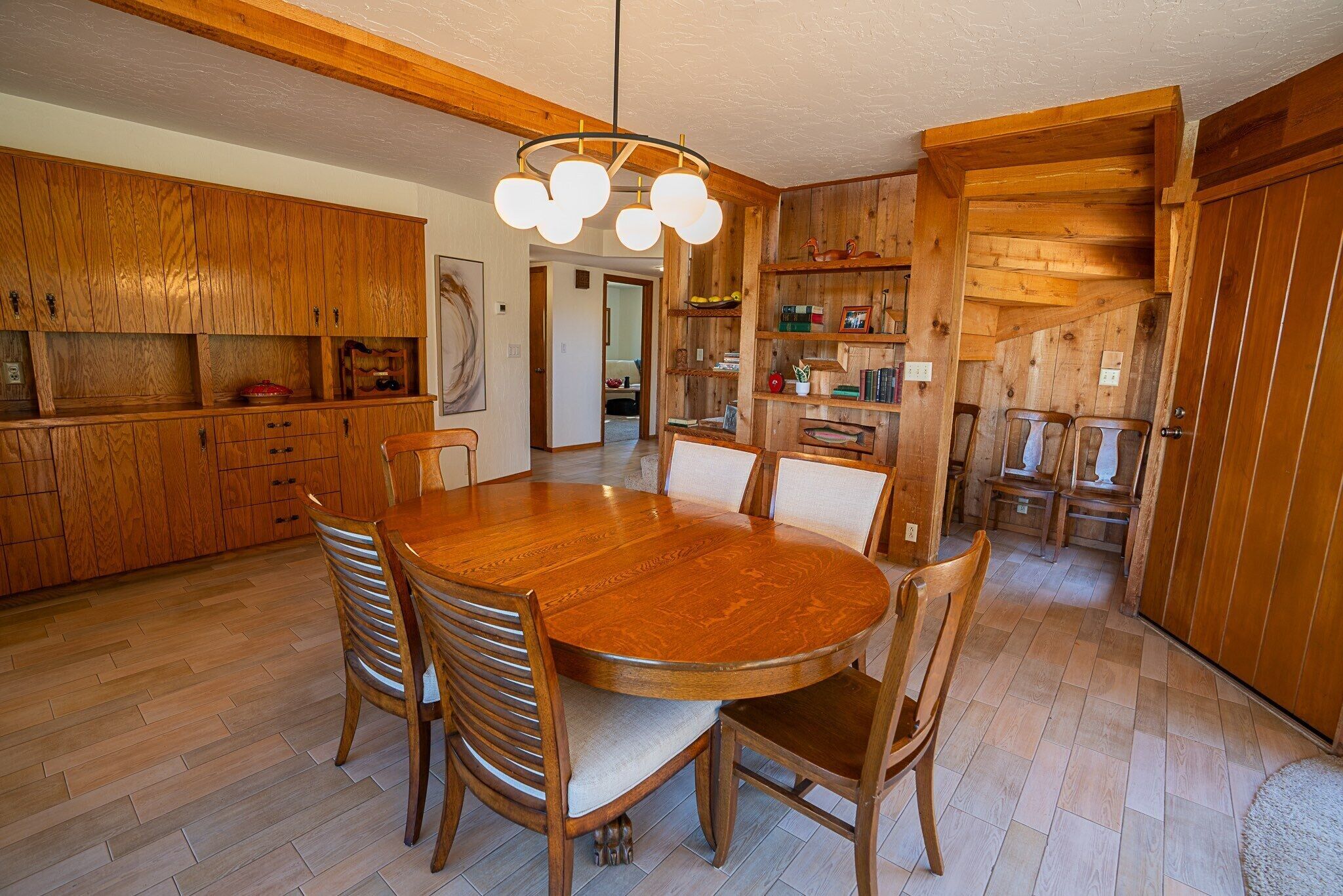 Un interior de madera con una mesa redonda para comer, sillas y una lámpara colgante.