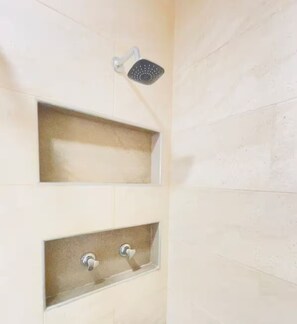 Eine Dusche mit Handbrause und zwei rechteckigen Waschbecken.