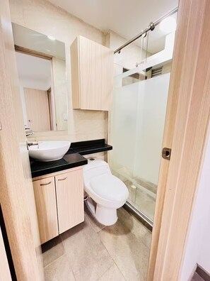 A modern bathroom with a sink, toilet, and glass shower enclosure. - Close to the airport and terminal, modern and quiet. (Bogotá)