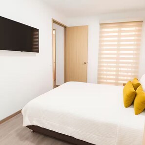A bedroom with a bed, a door, and a window with blinds. - Close to the airport and terminal; modern and quiet. (Bogotá)