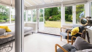 Ein Wintergarten mit einer Couch, Sesseln und einem Teleskop.