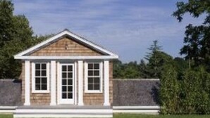 Een klein, laag gebouw met een puntige kap en een veranda.