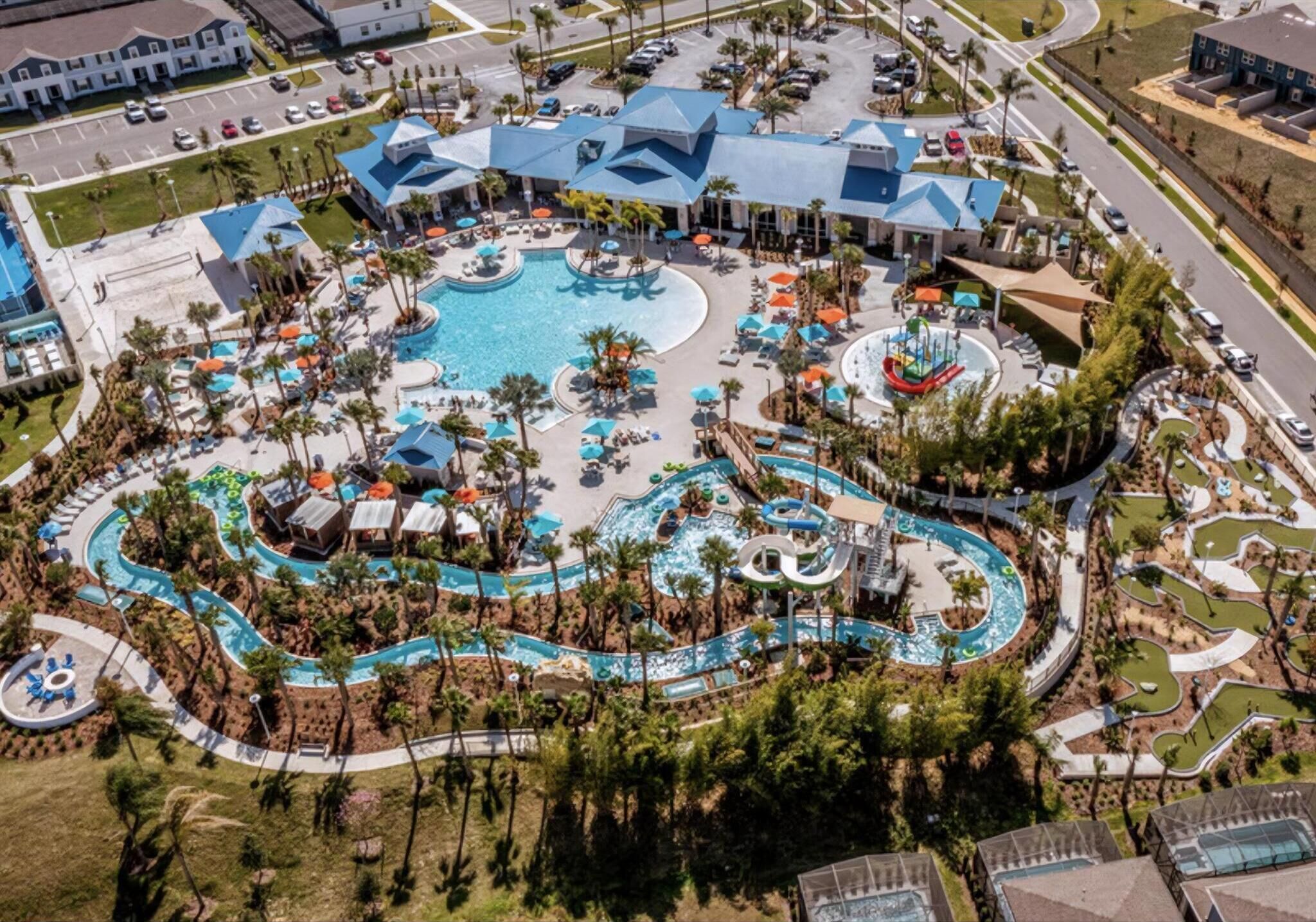 Vue aérienne d’un complexe hôtelier doté d’une piscine centrale, de plusieurs toboggans aquatiques et de divers espaces de détente.