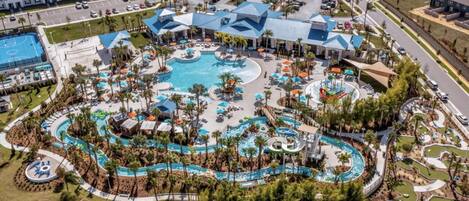 An aerial view of a resort with a central pool area, multiple buildings, and a parking lot.