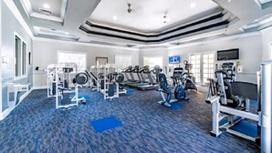 Un gimnasio amplio con diversos equipos de ejercicio, ventanas grandes y un diseño moderno en el techo.