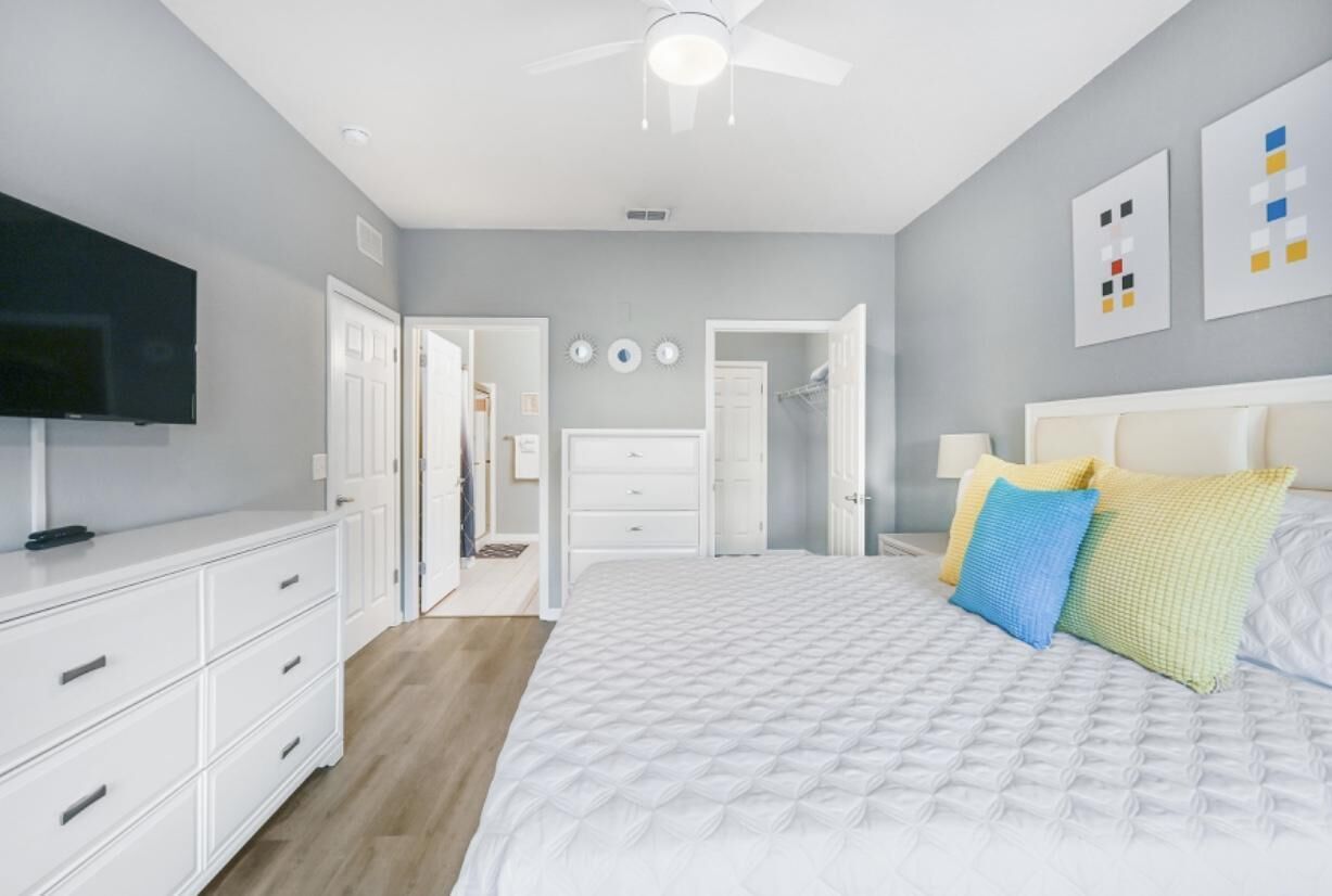 Une chambre à coucher avec un lit, une commode blanche et un téléviseur.