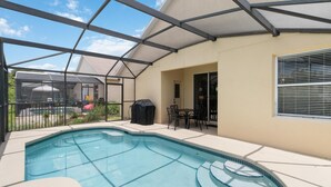 A swimming pool with a glass enclosure, a covered patio area, and a view of a neighboring house. - 5/3 Pool Home Located in Sunset Ridge Community! (Davenport)