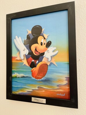 Une reproduction d’œuvre d’art de la collection Disney, encadrée, représentant Mickey Mouse dans une pose dynamique, avec une plage et l’océan en arrière-plan.