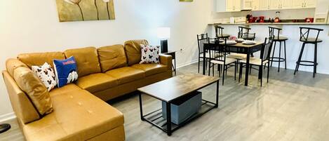 Una sala de estar con un sofá modular, una mesa de centro y una zona de comedor con mesa y sillas.