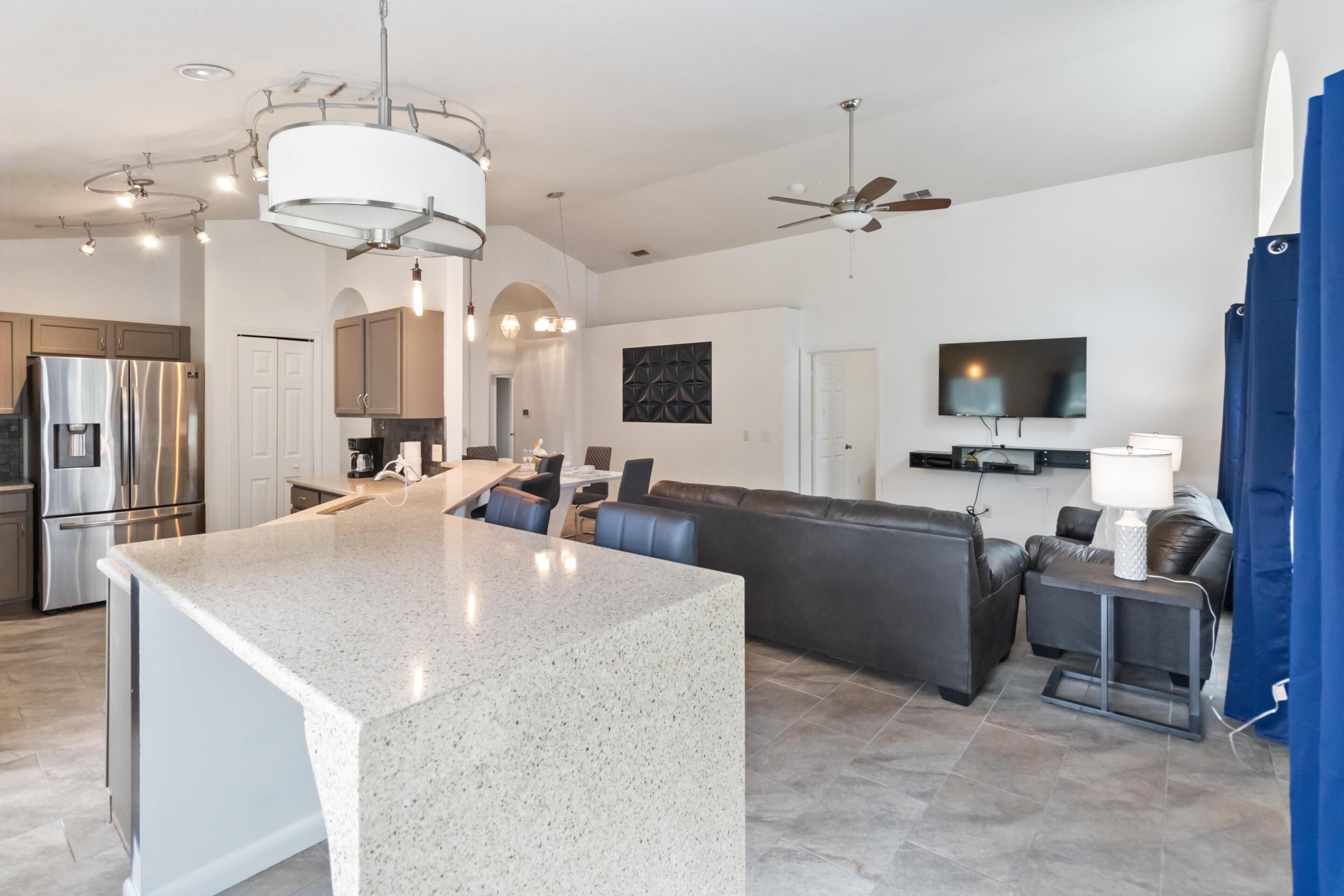 A modern kitchen with stainless steel appliances, a central island, and a dining area with a sofa and chairs.