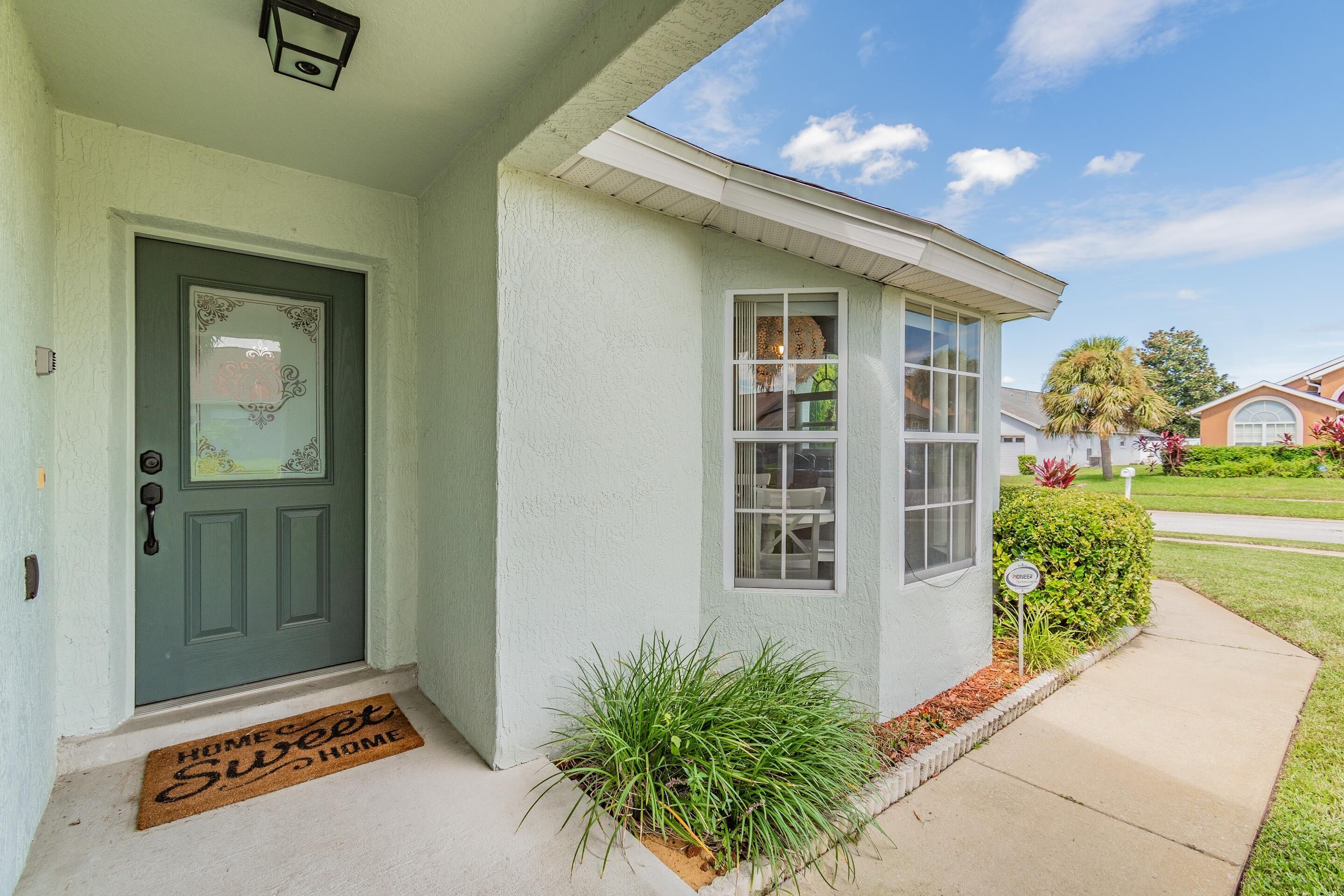 A house with a green door, a small porch, and a doormat.