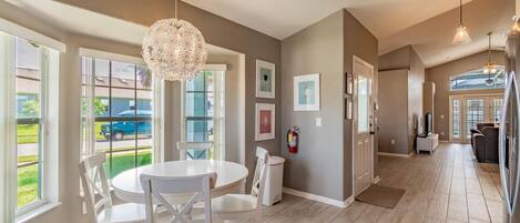 A spacious kitchen with a dining area, large windows, and a chandelier.