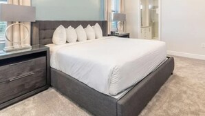 A modern bedroom with a large bed, bedside tables, and a mirror. - Amazing 4/3 Home at Reunion!! With Private Pool, Near Disney and Universal!! (Kissimmee)